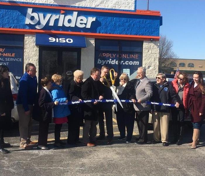 Local dignitaries and management cut the ribbon on a newly purchased auto dealer 