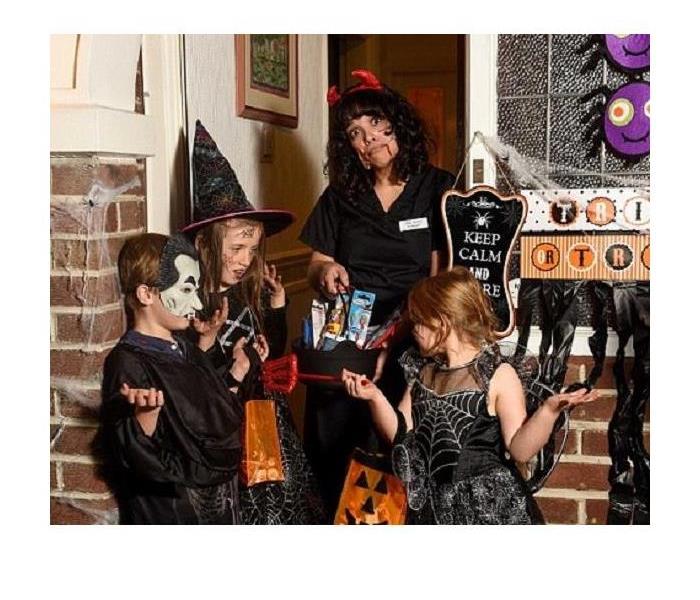 Several Trick or Treaters at a door collecting candy