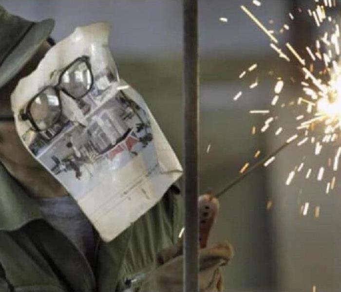 A person welding with a paper mask instead of the proper equipment