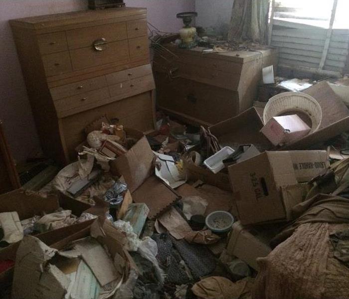 A bedroom of a hoarder, filled with furniture and garbage